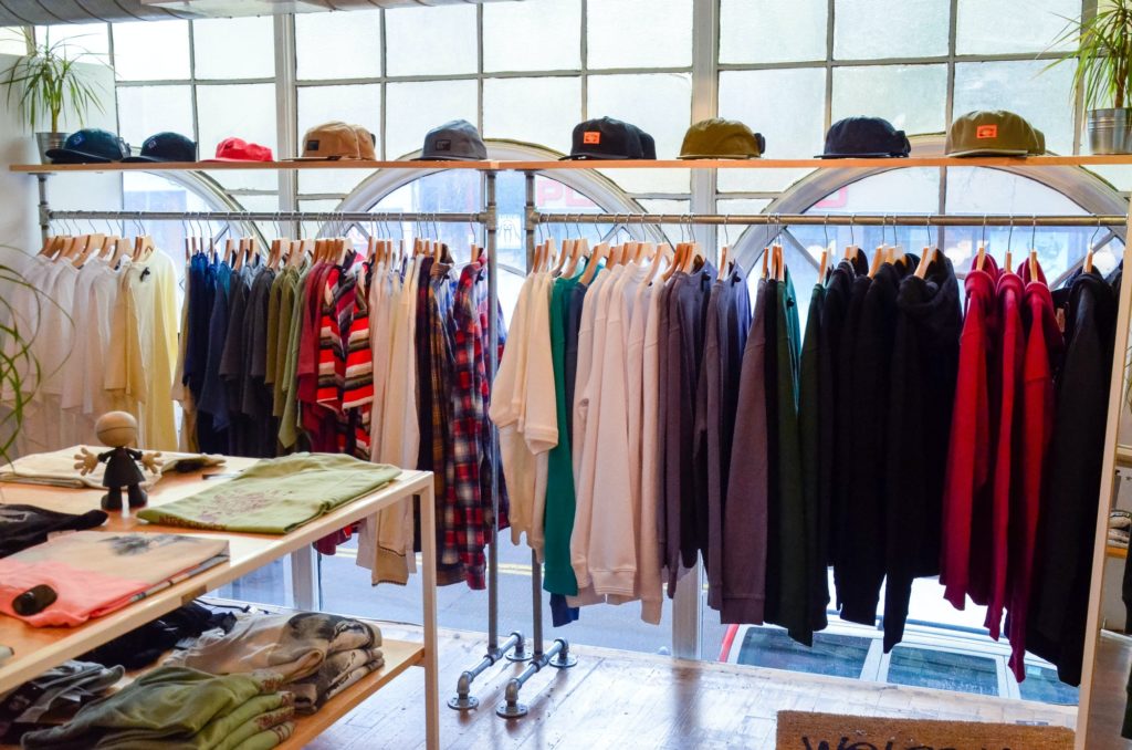 Retail shopping, clothes on a rack in a store with hats lined up on top